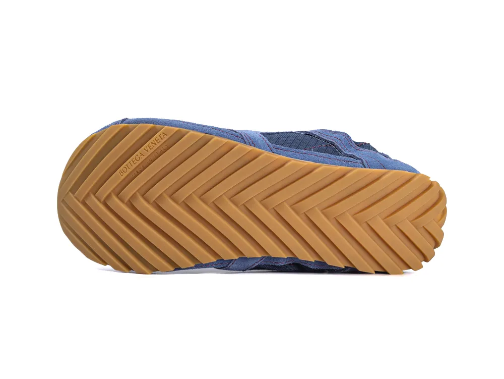 Blue canvas sneaker with a tan rubber sole, featuring a zigzag pattern.