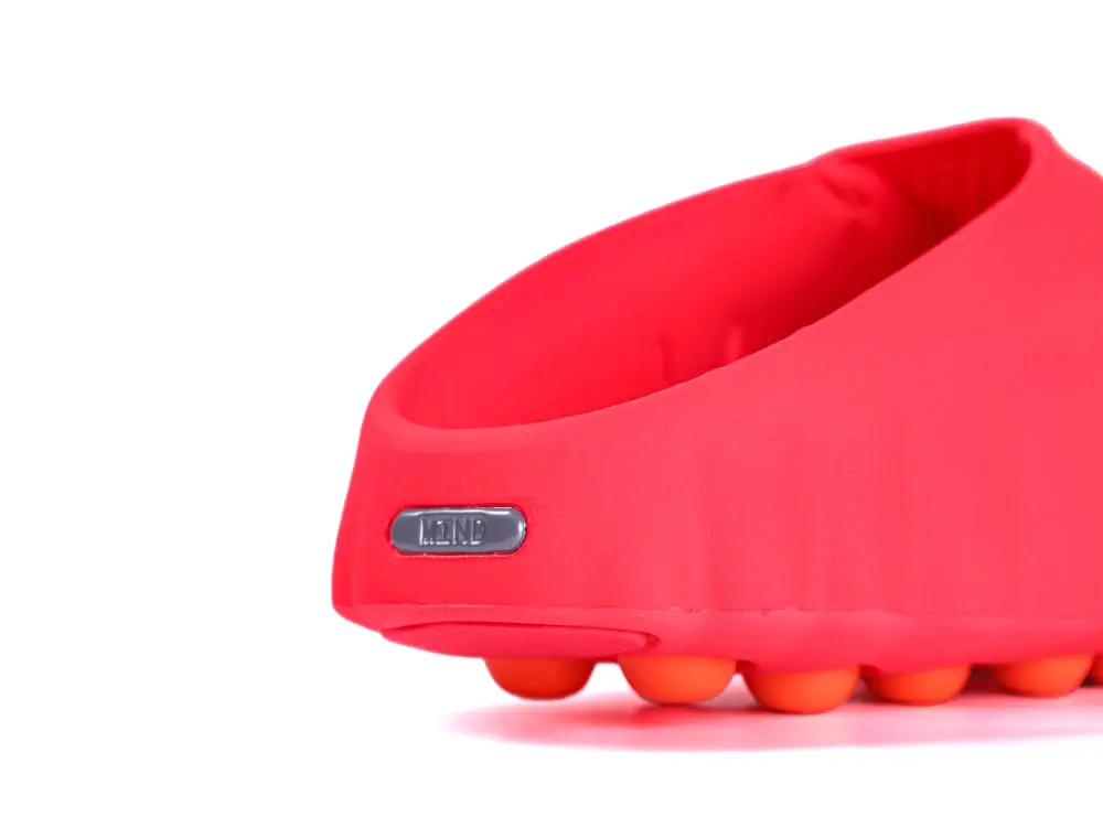 Red rubber sandal with orange cushioned sole and a metal brand tag.