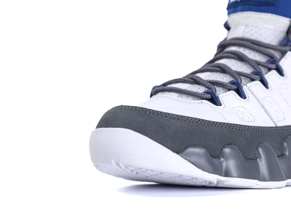 White and gray sneaker with blue accents, featuring a leather and suede upper.