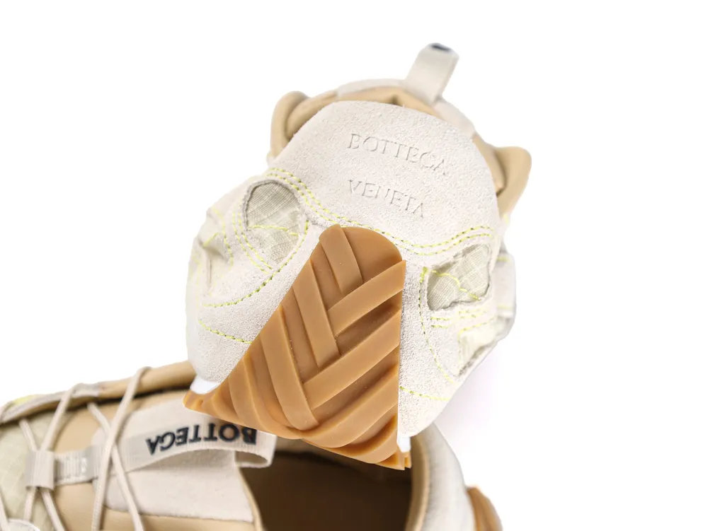 Beige suede sneaker with rubber sole, intricate stitching, and transparent mesh details.