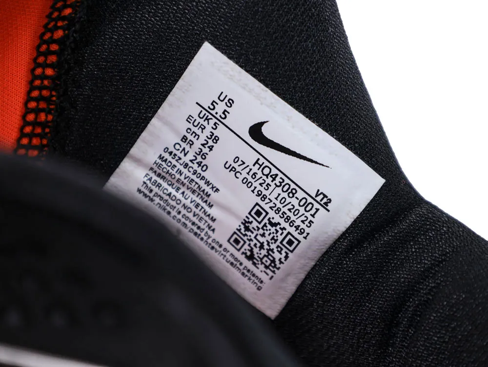 Label inside black fabric shoe with orange interior, showing size and brand information.