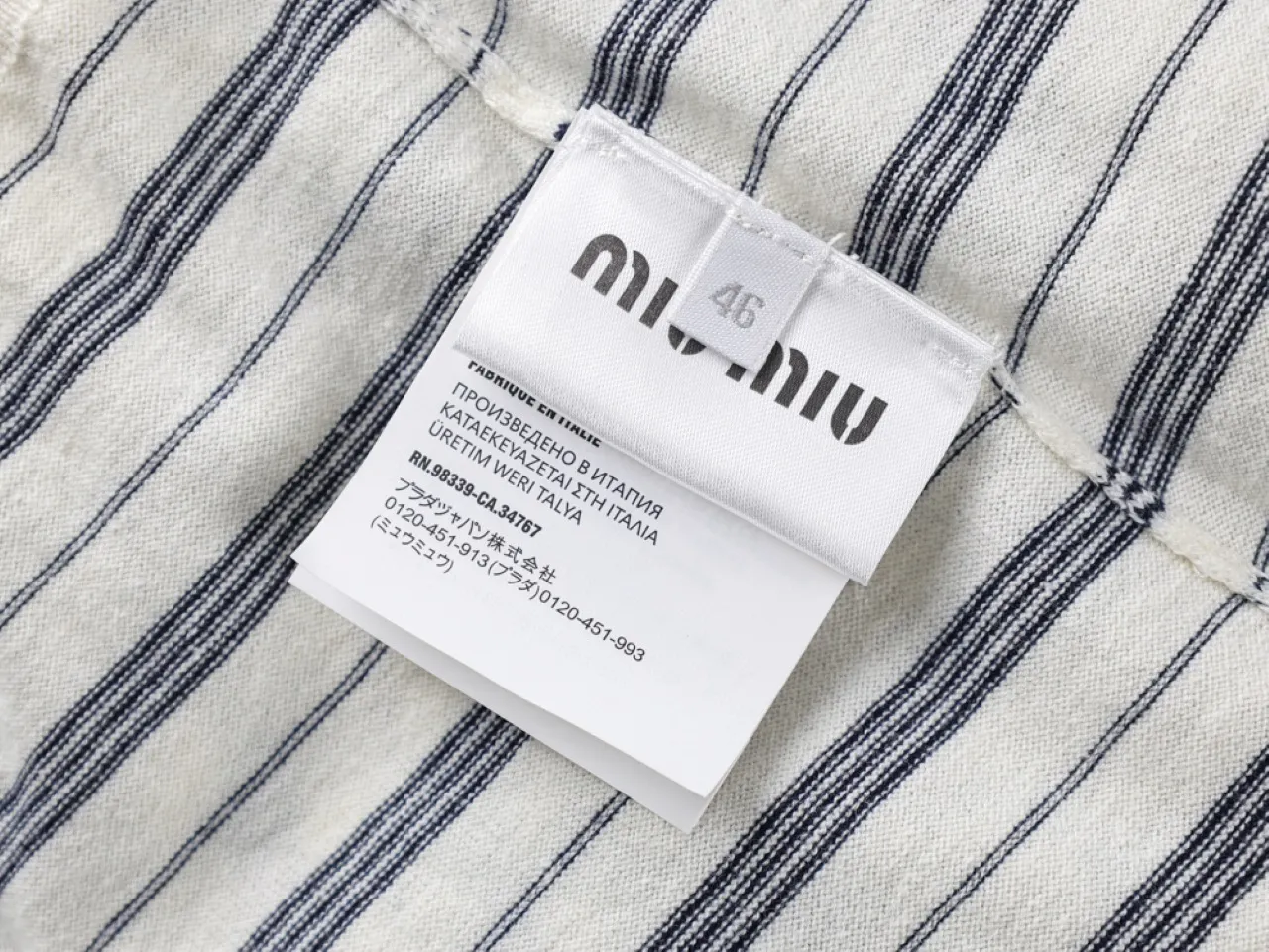 White fabric with navy stripes, cotton material, featuring a care label.