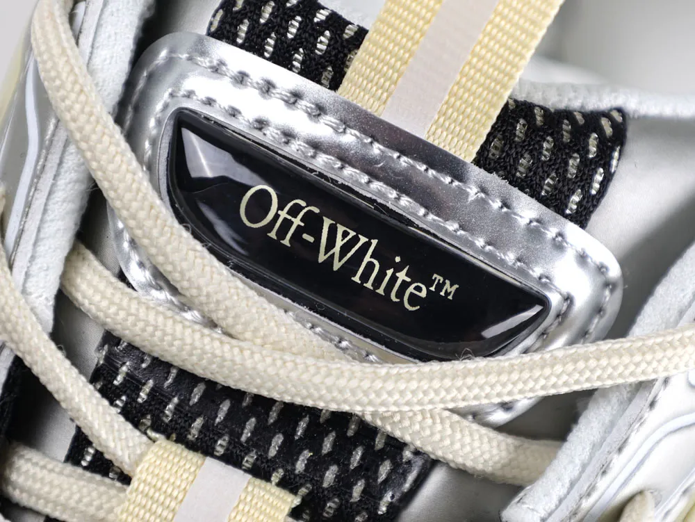 Close-up of sneaker with silver trim, cream laces, and black mesh detailing.
