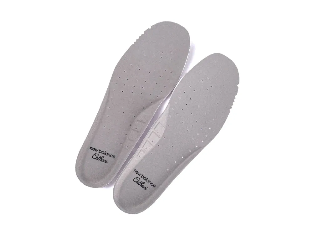 Gray foam shoe insoles with perforations and branding, providing cushioning and breathability.