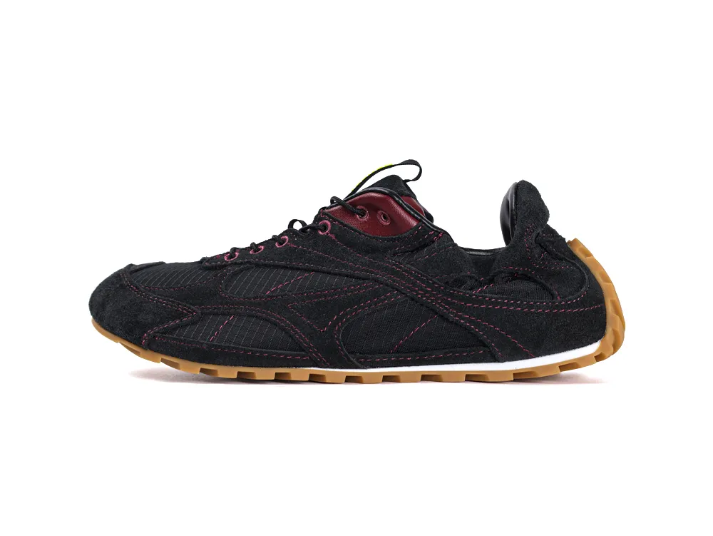 Black suede sneaker with red accents and brown rubber sole.