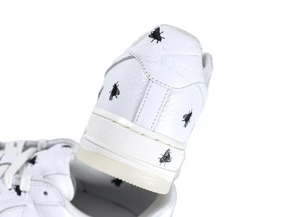 White leather shoes with black embroidery detailing on the heel and sides.