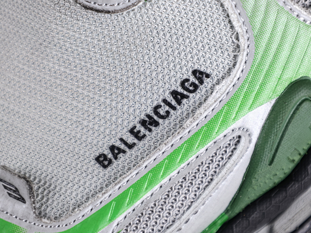 Close-up of a gray and green mesh sneaker with visible branding text.