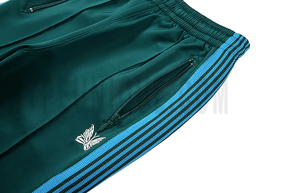 Close-up detail of the track pants pocket and delicate butterfly embroidery.