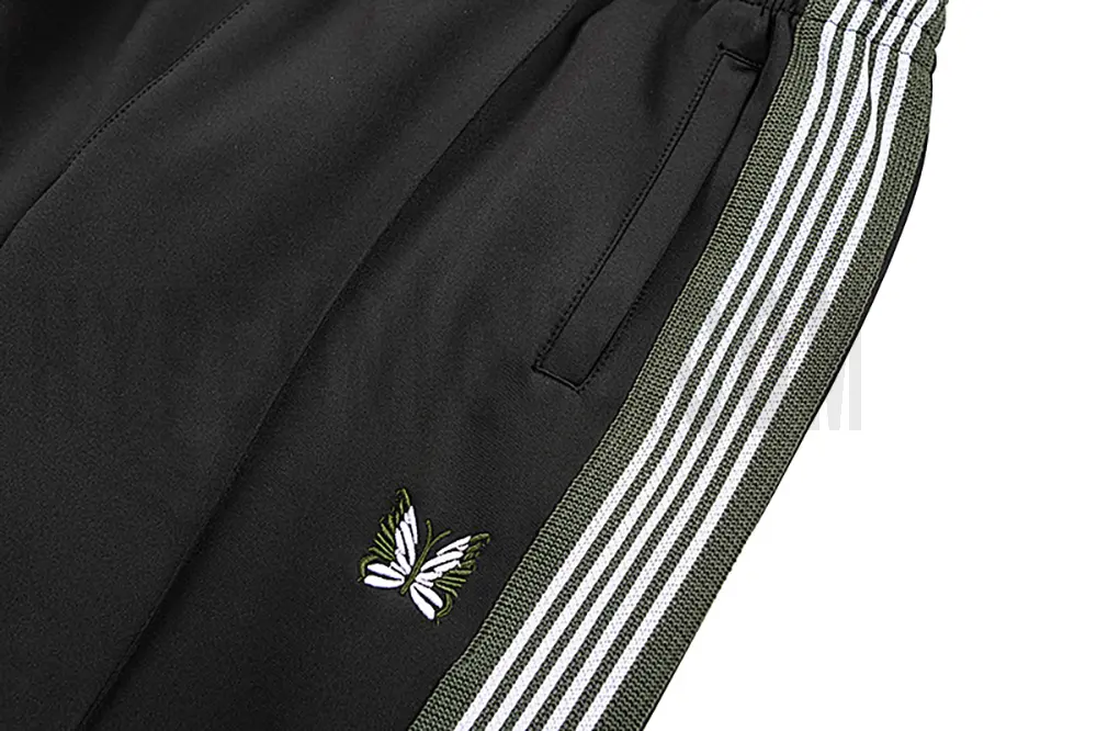 Detailed view of the pocket and intricate butterfly embroidery on the track pants.