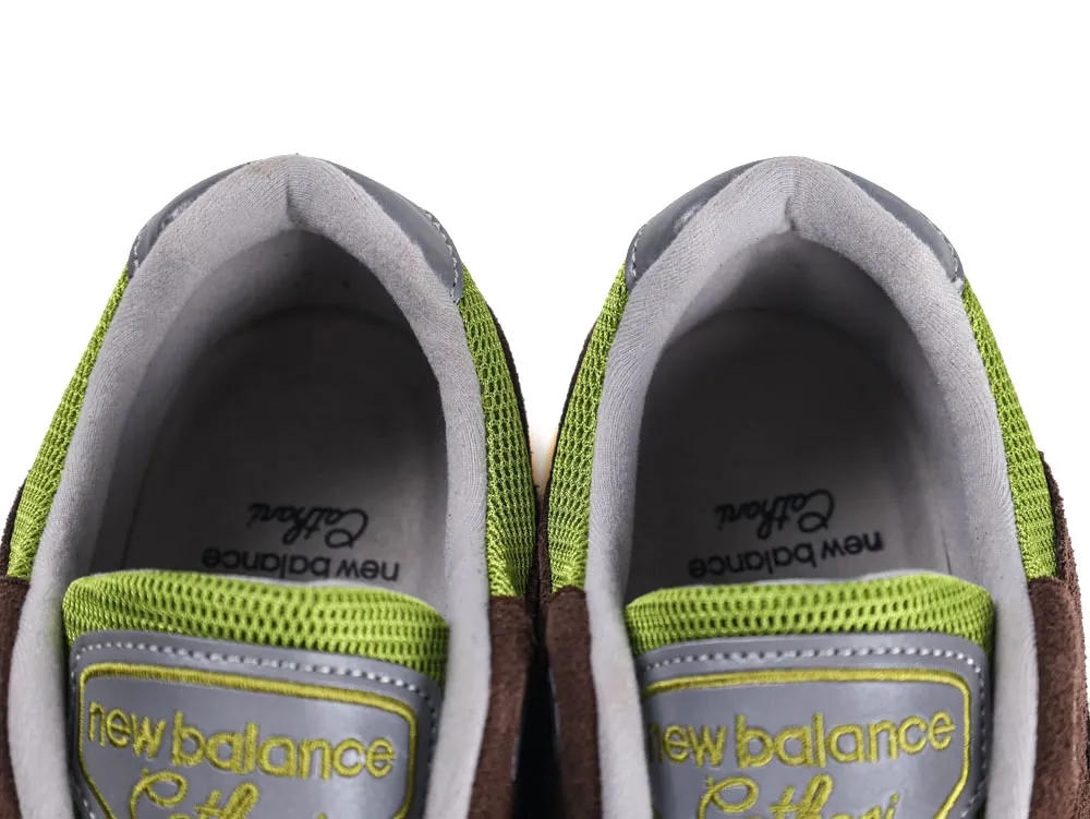 Close-up of grey and green mesh sneakers with embroidered logo on tongue.