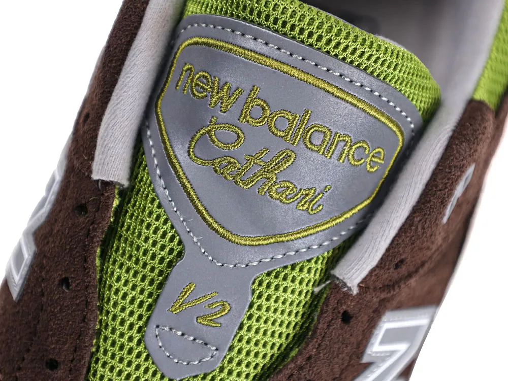 Close-up of brown suede and green mesh sneaker tongue with logo.