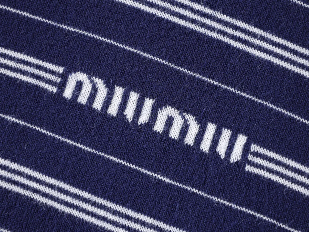 Navy blue knitted fabric with white stripes and embroidered text detail.