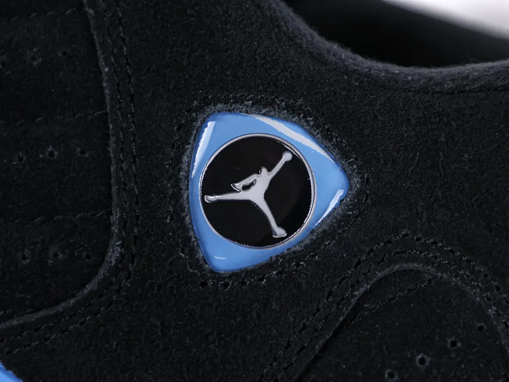 Close-up of a black suede shoe with a blue plastic emblem detail.