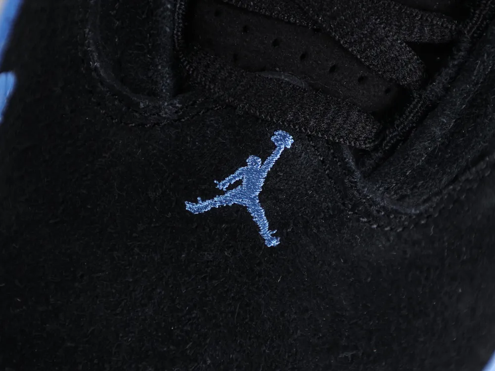 Close-up of a black suede shoe with light blue embroidered logo detail.