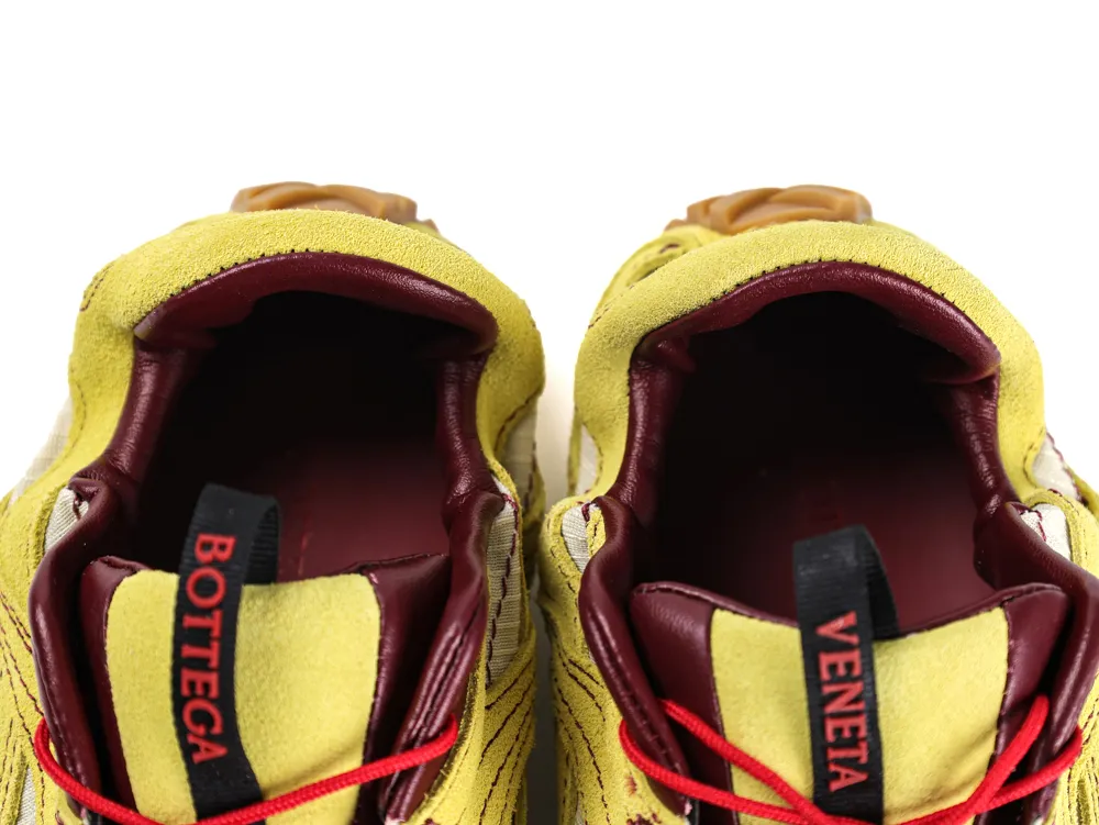 Yellow suede sneakers with burgundy leather interior and red laces visible from top.