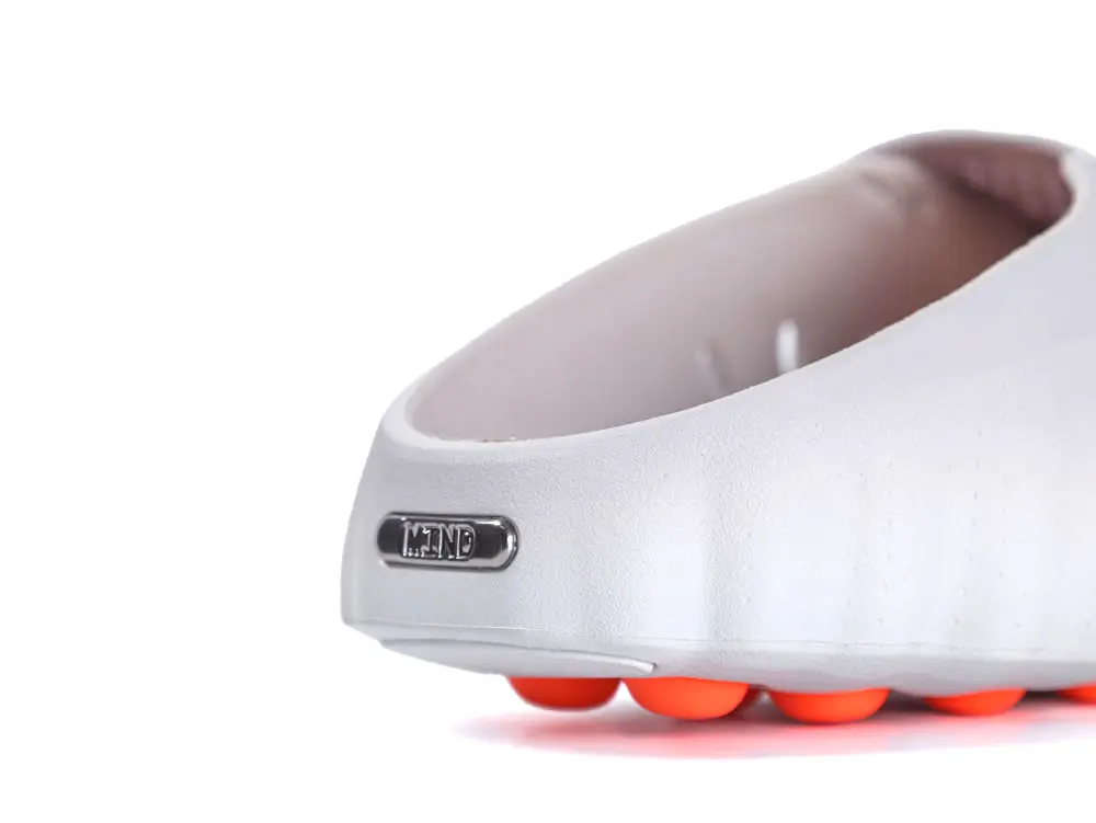 White rubber shoe with orange sole, featuring metallic logo detail.