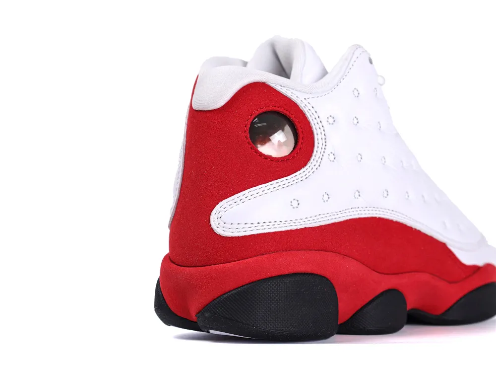 Red and white suede athletic shoe with black sole and circular heel detail.