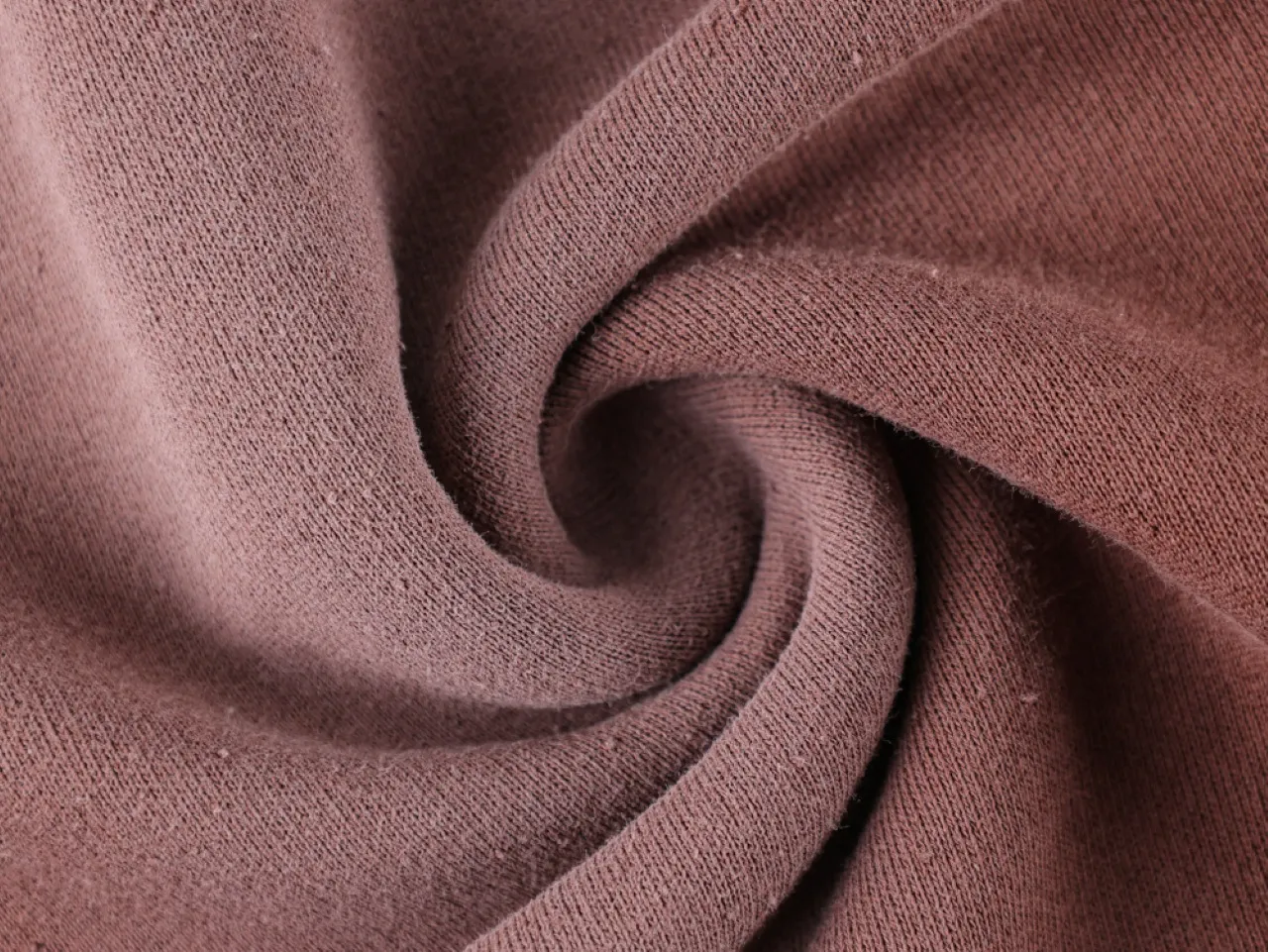 Close-up of brown cotton fabric, showing texture and weave pattern in a swirl.