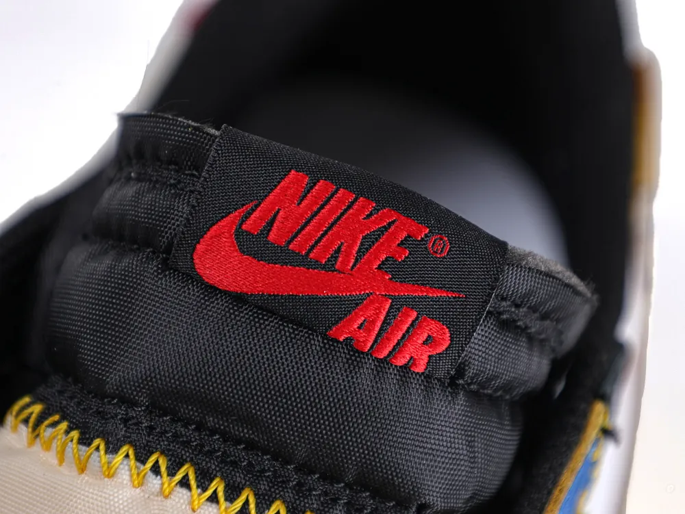 Black nylon tongue of a sneaker with red embroidered logo and yellow stitching.