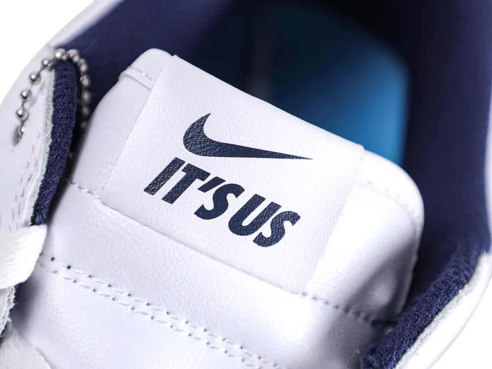 White leather shoe tongue with logo, featuring navy fabric lining and metal chain detail.