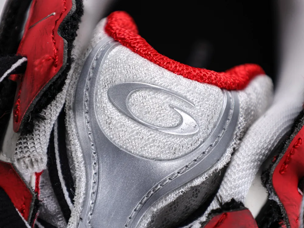 Close-up of a shoe tongue with red, silver, and mesh fabric details.