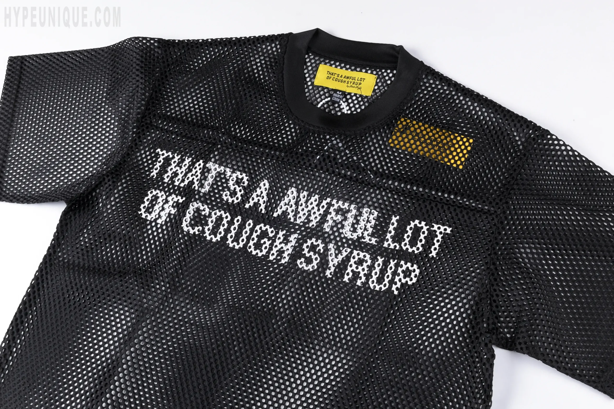 That's A Awful Lot of Cough Syrup Letter Mesh T-shirt features the official chest graphic. There's a yellow brand label on the left shoulder.