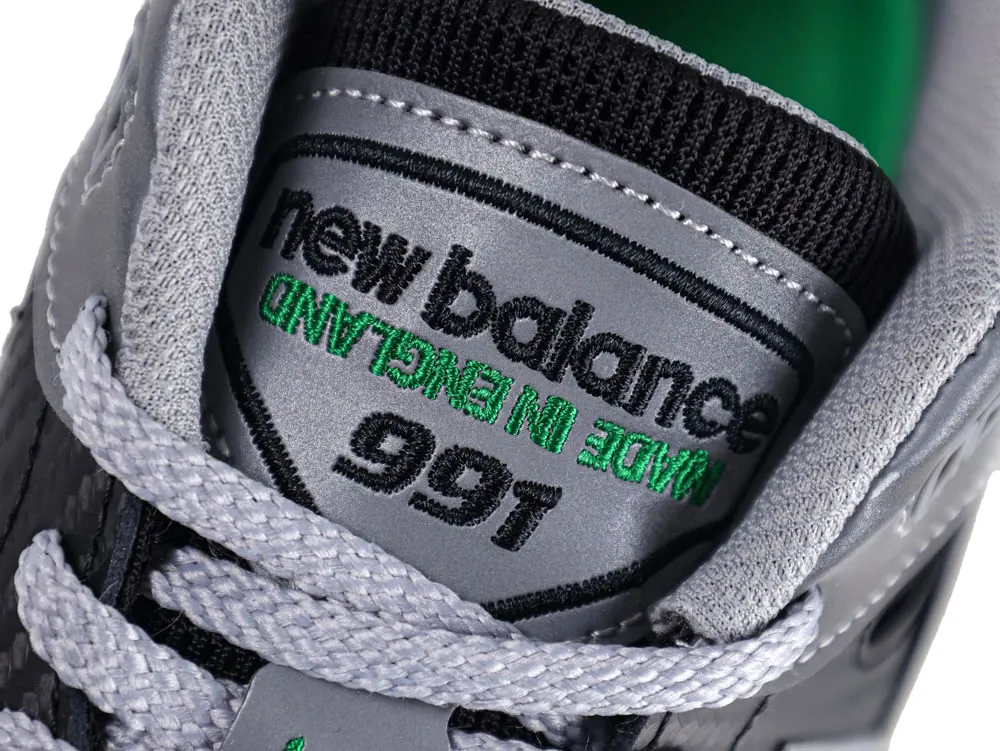 Gray sneaker tongue with embroidered branding, featuring light gray laces and stitching.