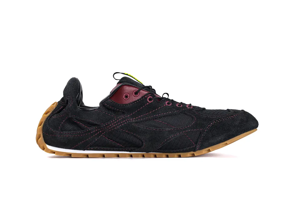 Black suede sneaker with burgundy eyelets and gum sole, featuring pink stitching.