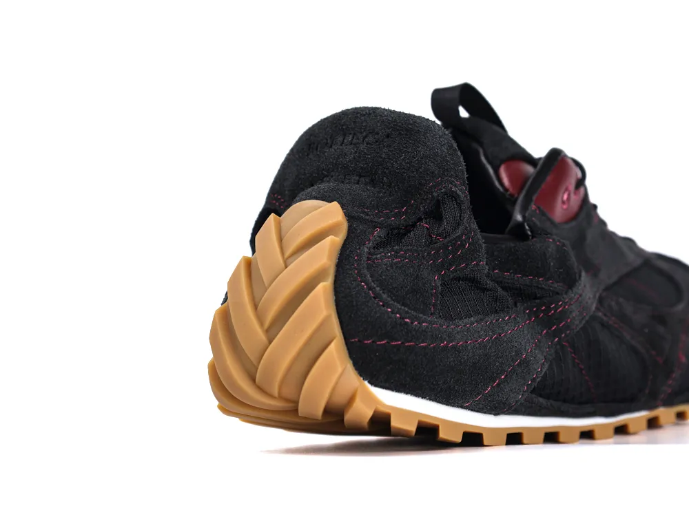 Black suede sneaker with a tan rubber sole and burgundy stitching details.