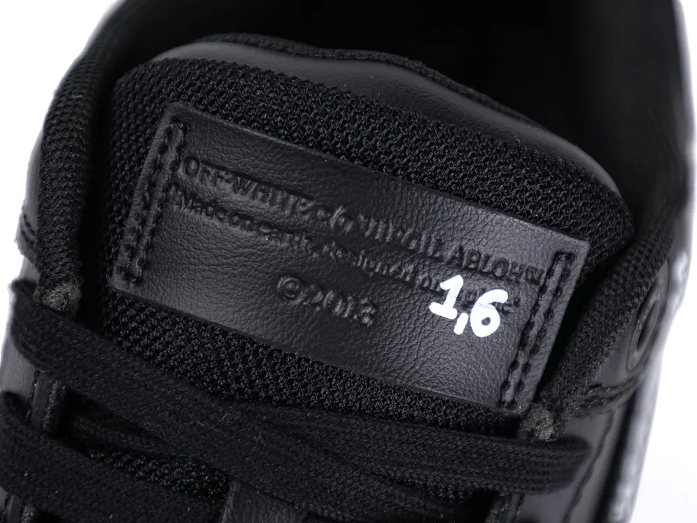 Close-up of black leather sneaker tongue with embossed text and white numbers.
