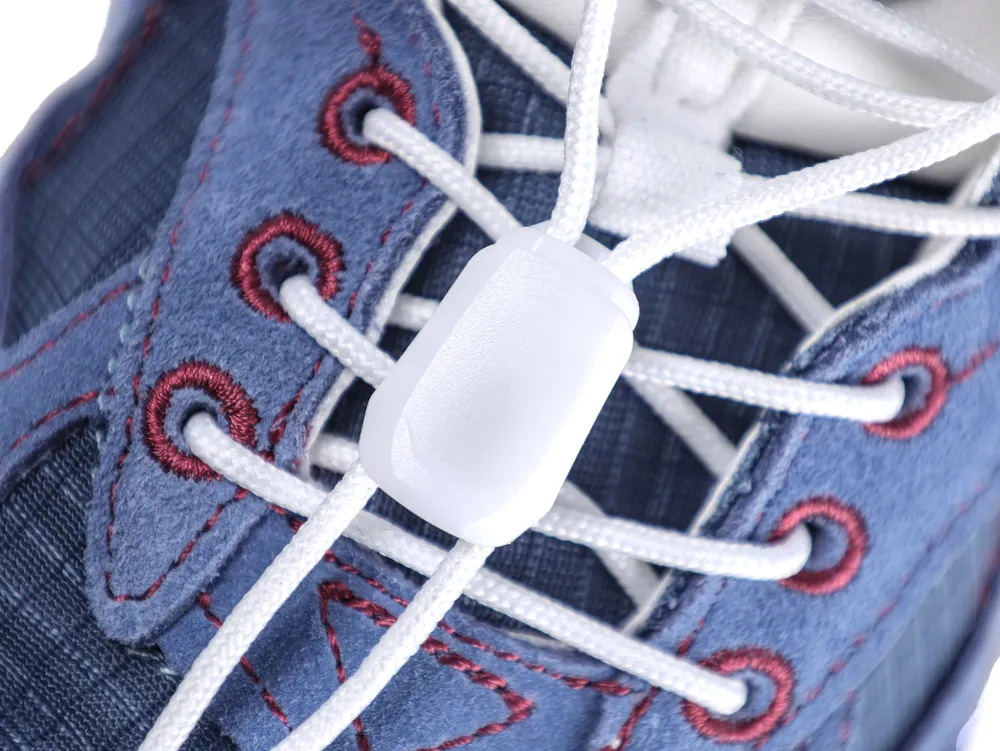 Close-up of blue fabric shoe with red stitching and white plastic lace lock.