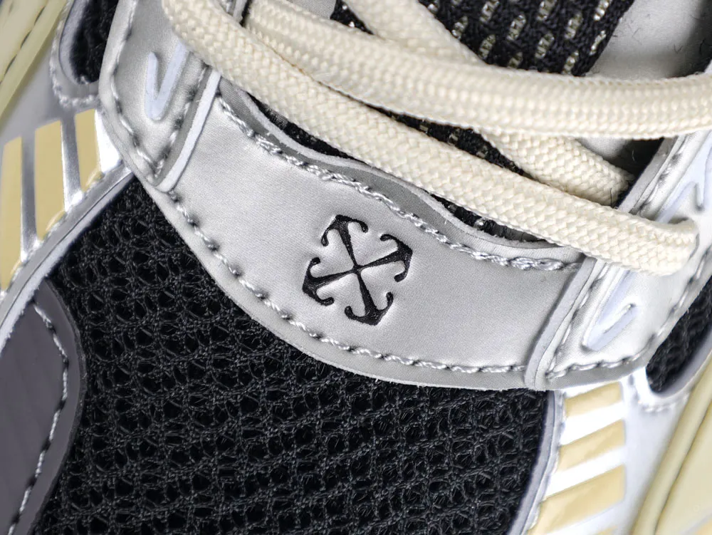 Close-up of sneaker with black mesh fabric, silver leather, and beige shoelaces.