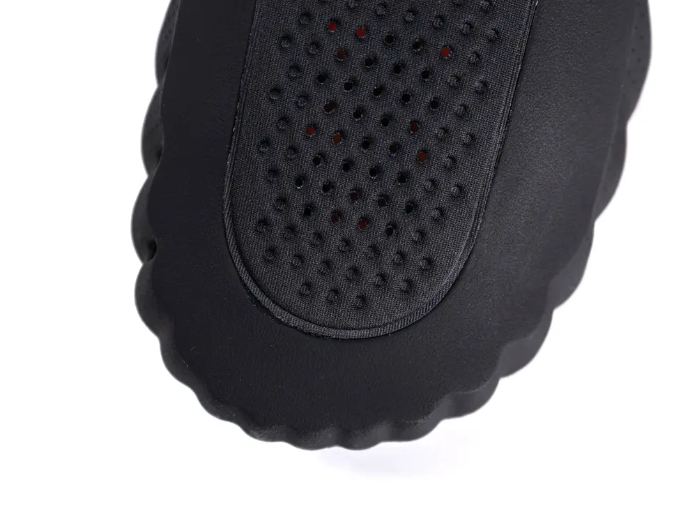 Black perforated upper shoe material with textured edge, showcasing sleek design.
