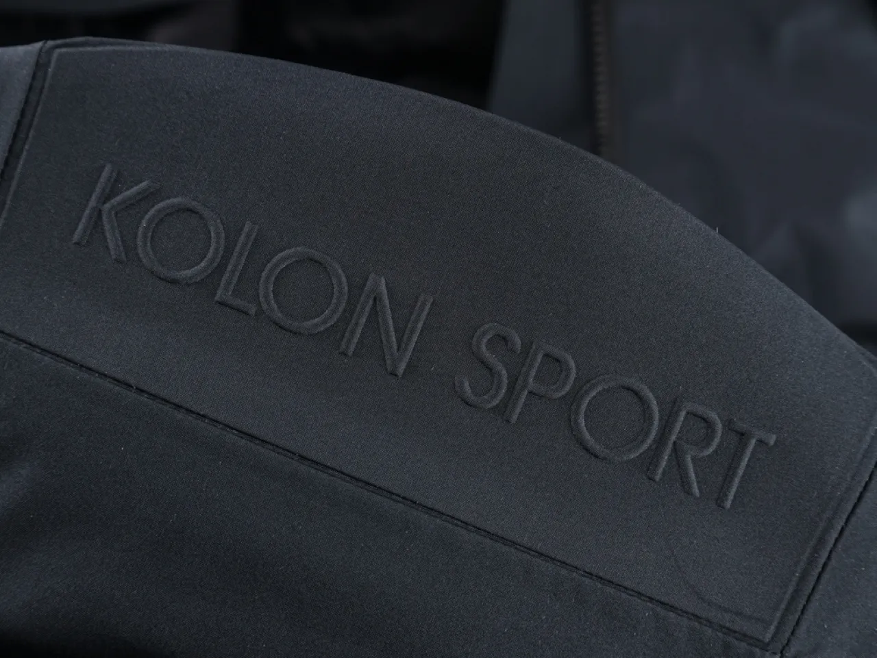 Dark fabric featuring embossed text with the brand name "KOLON SPORT"