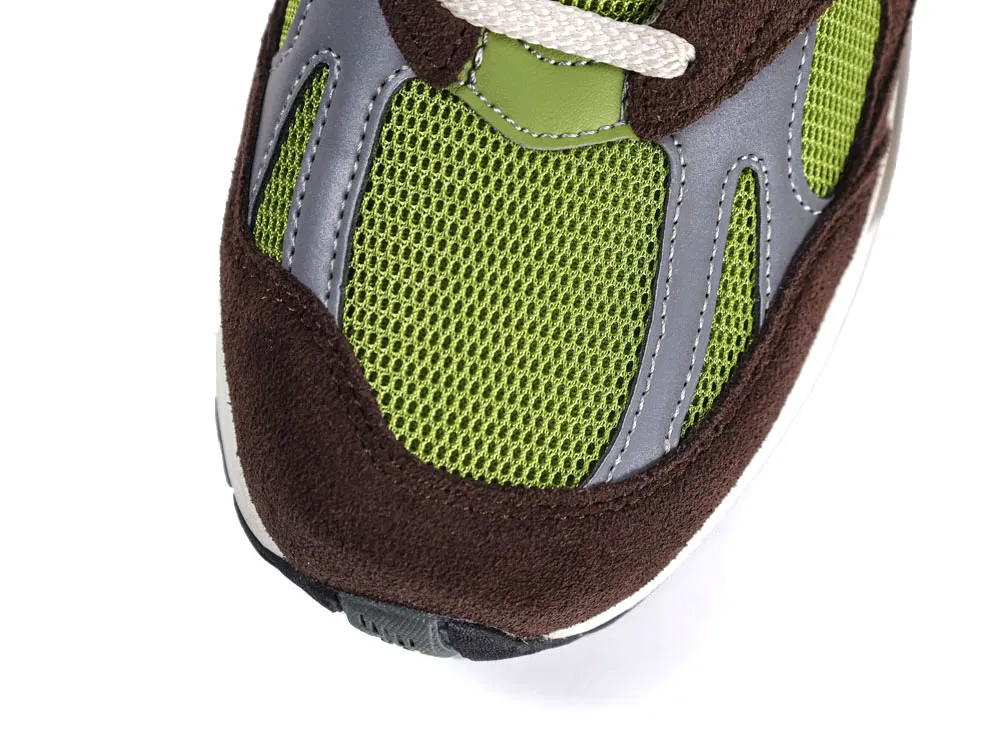 Close-up of sneaker toe with green mesh, grey synthetic, and brown suede material.