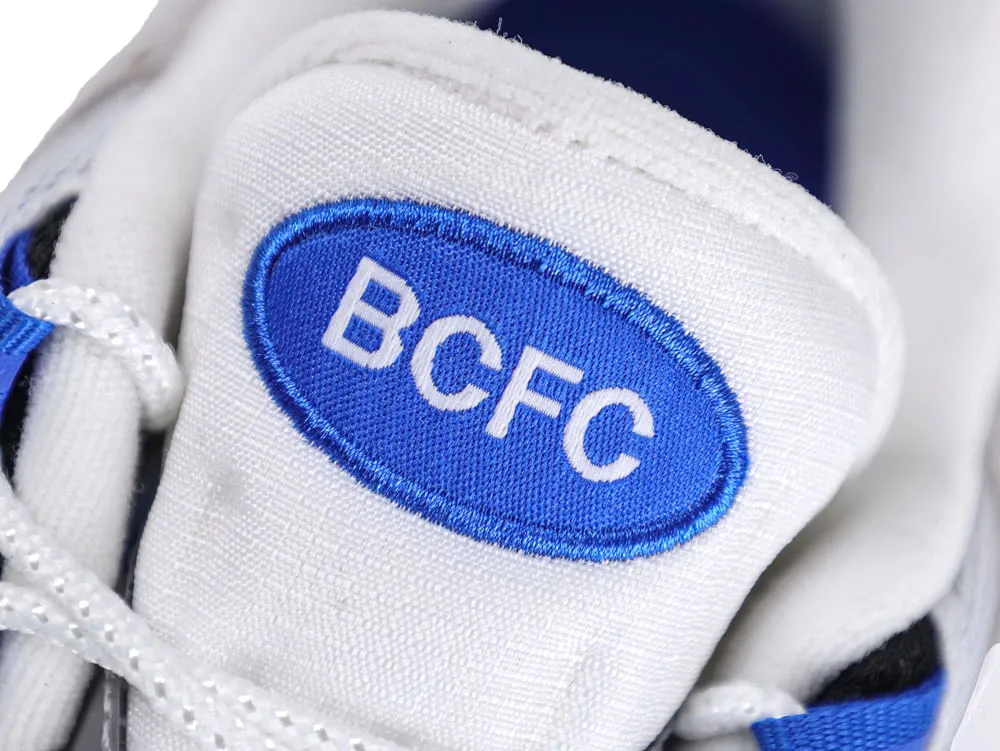 White fabric shoe tongue with blue and white embroidered logo.