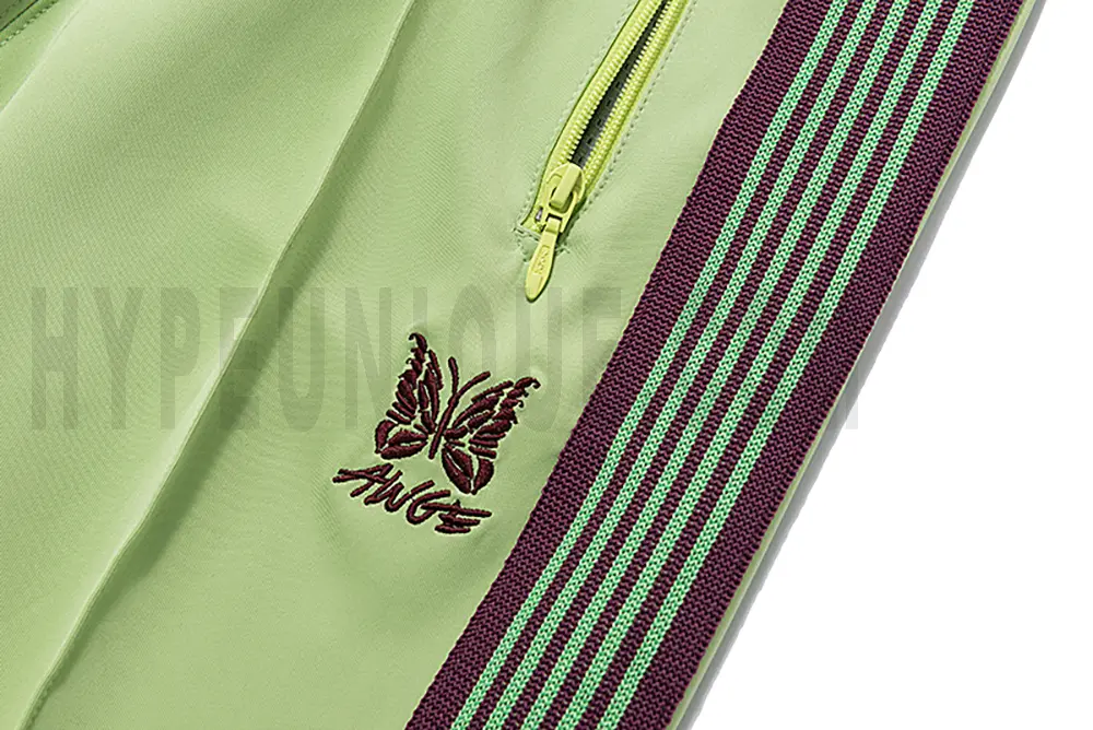 Close-up detail of the track pants pocket and delicate butterfly embroidery.