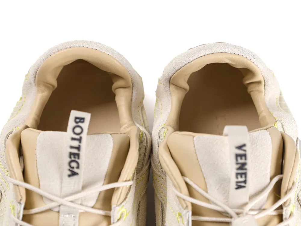 Beige sneakers with suede material and visible tongue tabs displaying brand name.