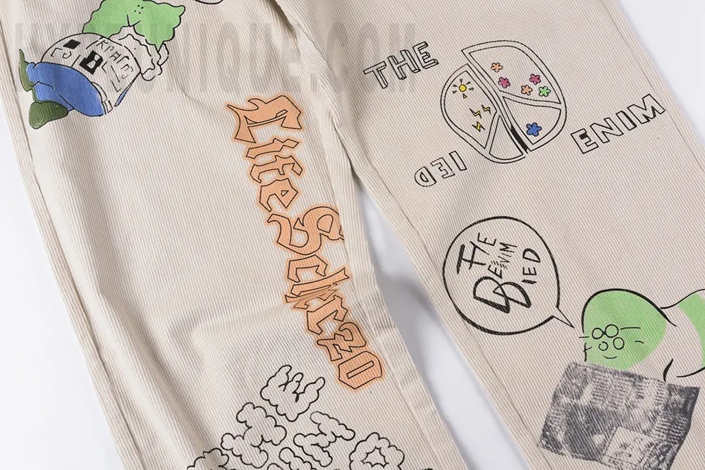 Front pant leg graffiti detail area of the KAPITAL Ivy Wide-Leg Pleated Printed Cotton-Corduroy Trousers.