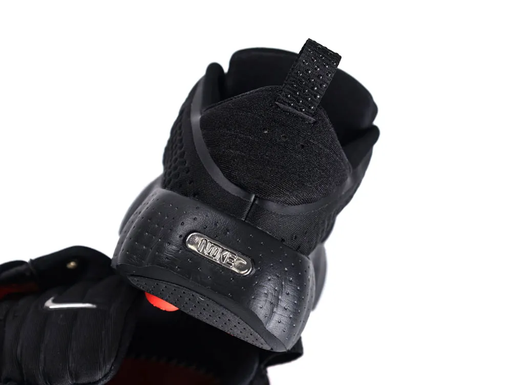 Black sneaker with textured fabric, rubber sole, and heel tab details.