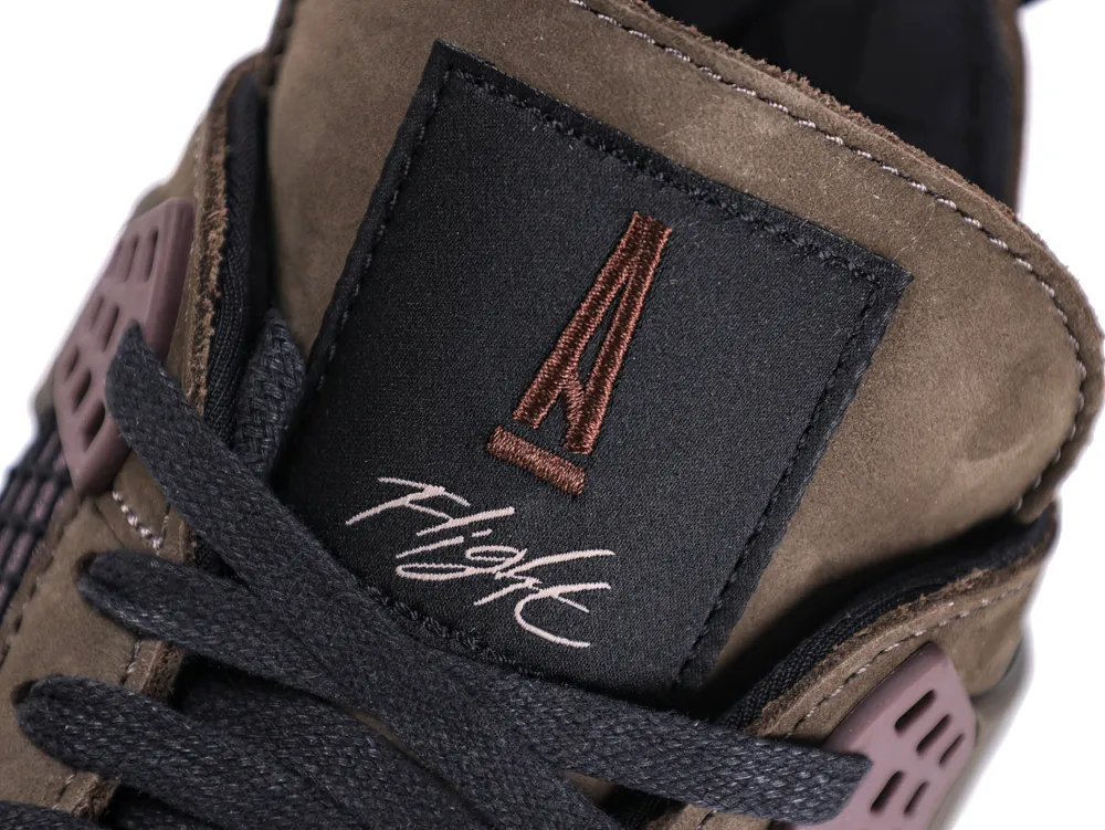 Close-up of a brown suede shoe tongue with black laces and embroidered logo.
