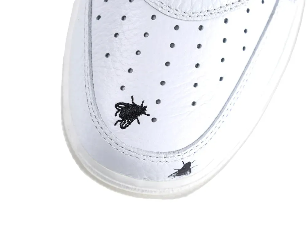 White leather sneaker with perforated toe box and black insect design.
