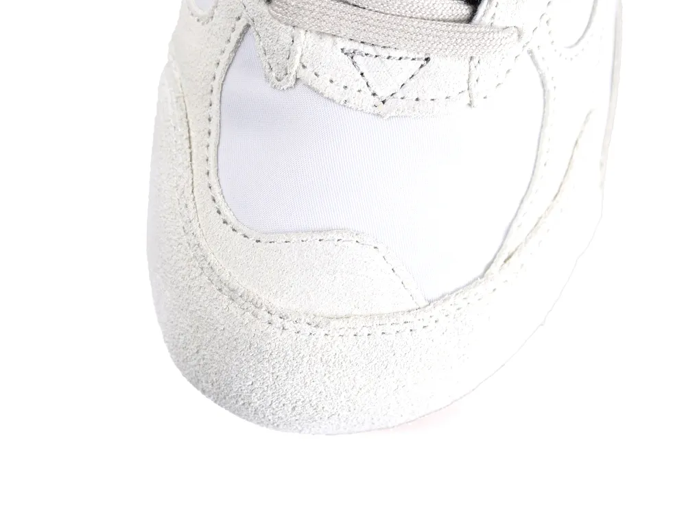 Close-up of a white suede shoe with fabric detailing around the toe area.