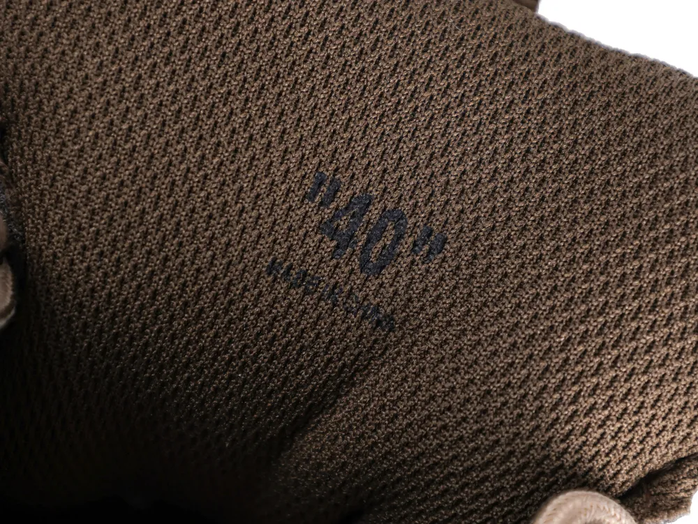 Brown textured fabric with black printed text, part of a glove or garment.