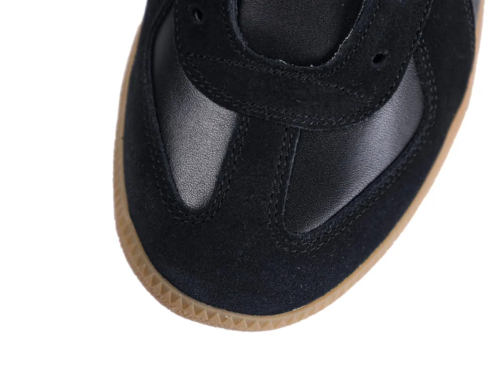 Black suede and leather sneaker with a brown rubber sole close-up.