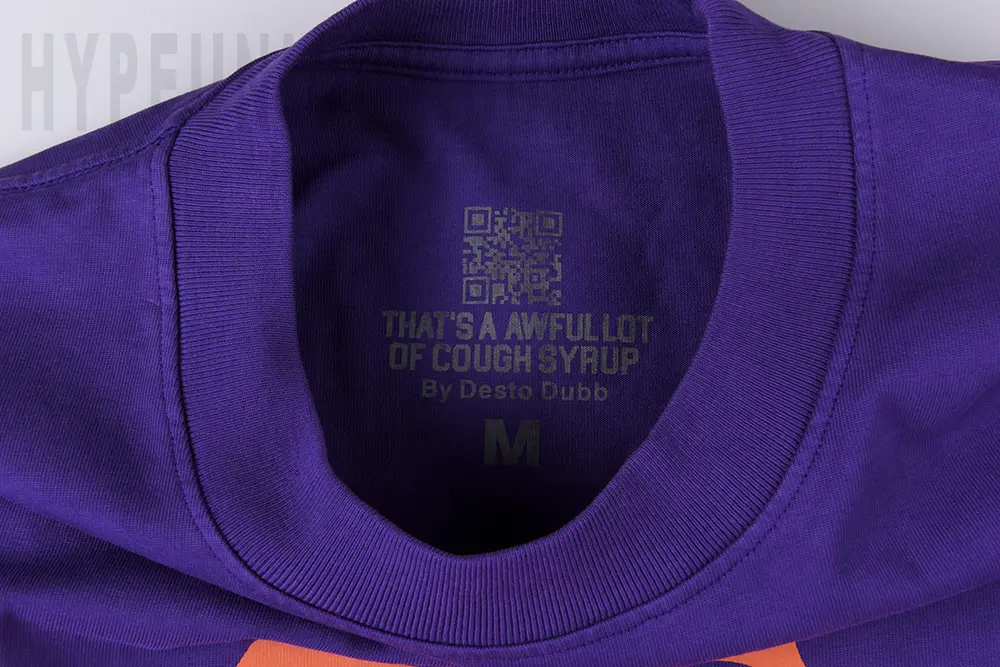 Close-up view of the neck label on the That’s A Awful Lot of Cough Syrup Skull Ribs T-shirt, including the brand QR code.