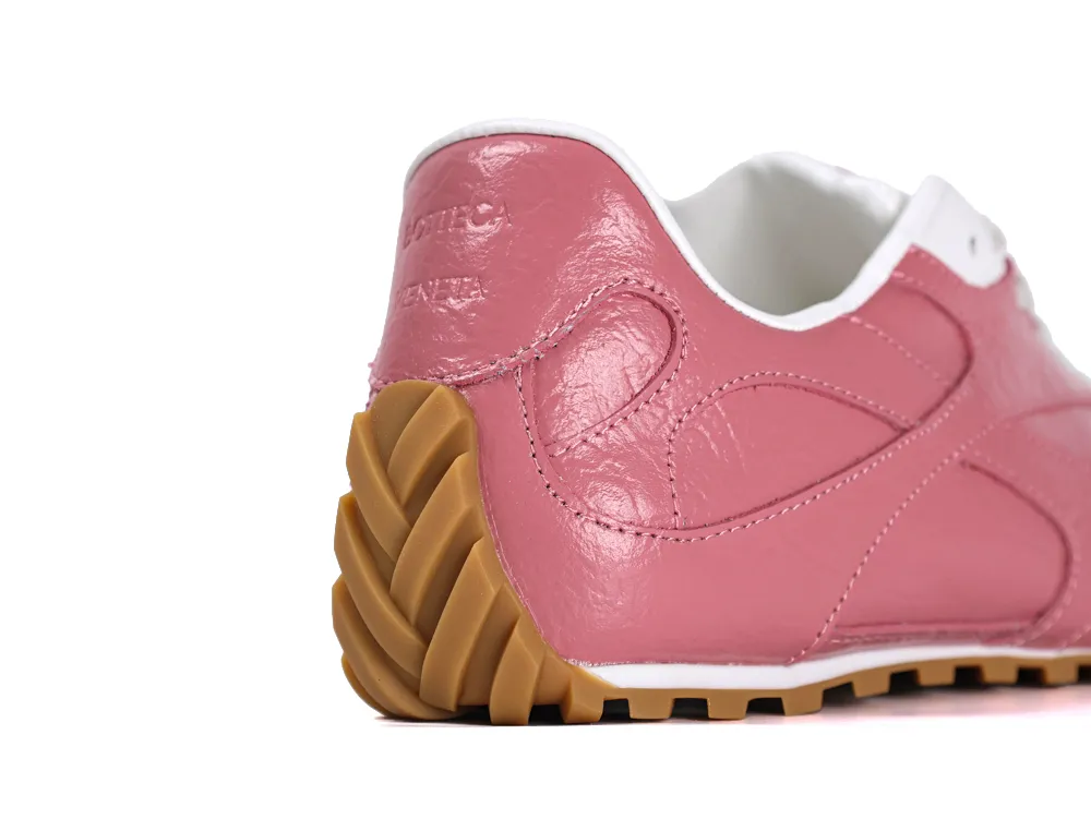 Rear angle of the pink leather heel counter with white trim and a textured gum outsole.