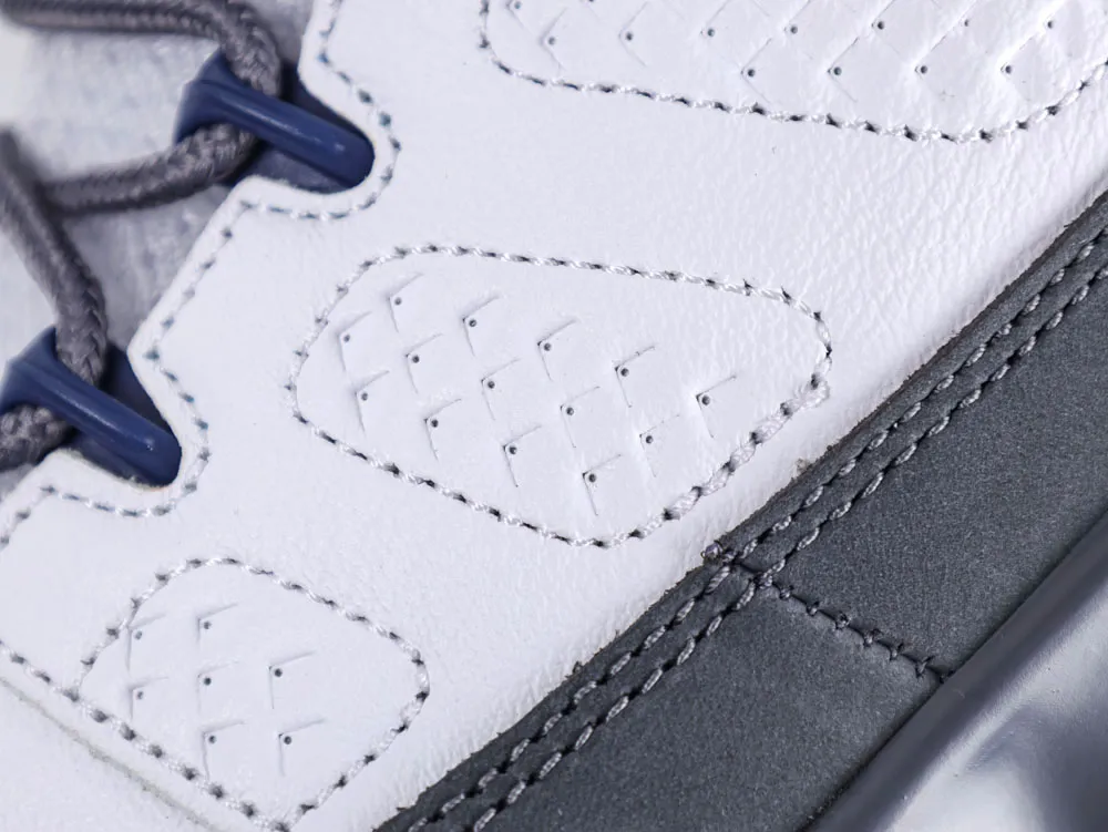 Close-up of a white leather shoe with gray laces and blue eyelets.