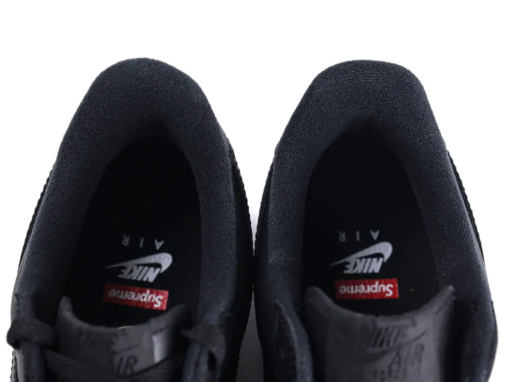 Black suede sneakers with branded insoles, featuring logos from Nike and Supreme.