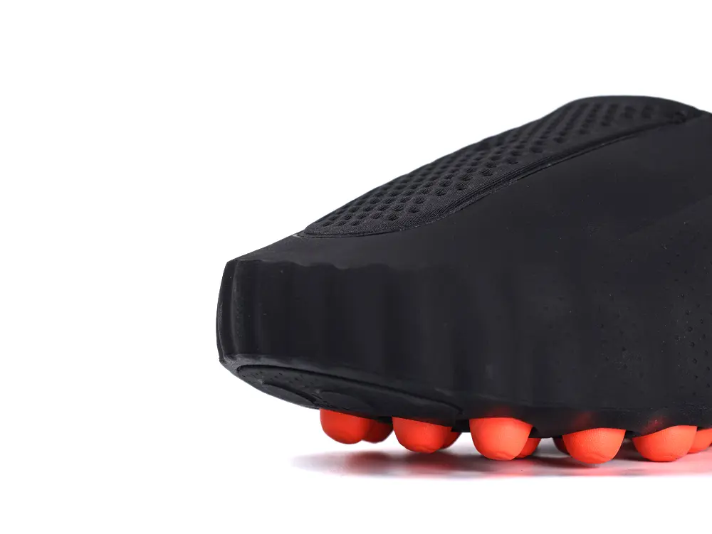 Black and orange shoe bottom with rubber studs, textured for grip and durability.
